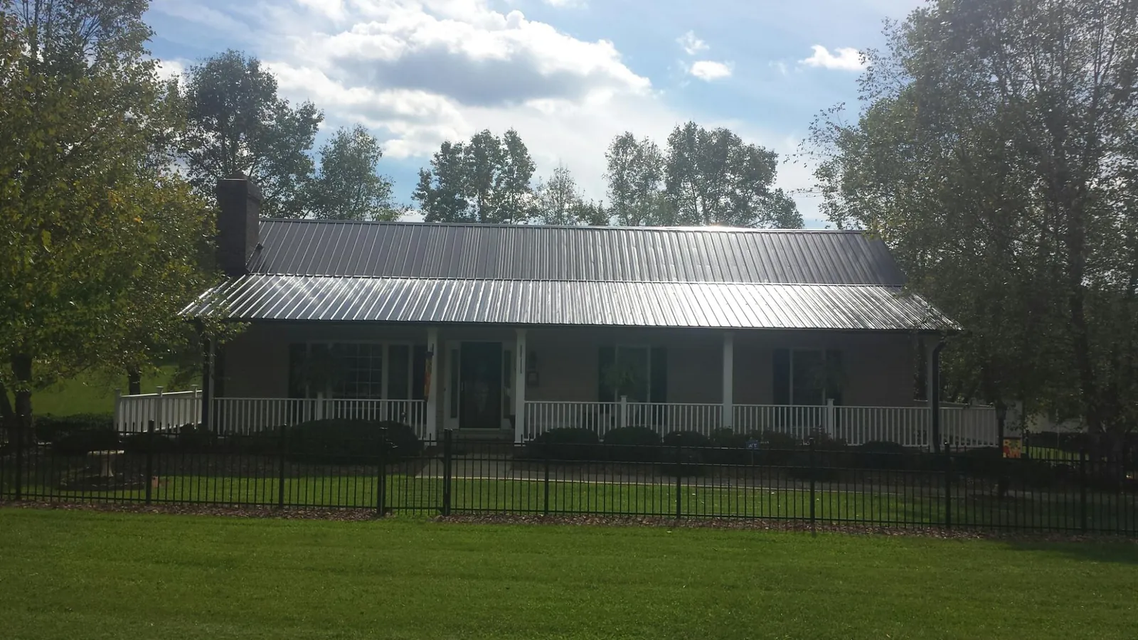 Gray metal roof on a brick ranch with a full width front porch — Gutter Guard Installation work by our crew in Randall